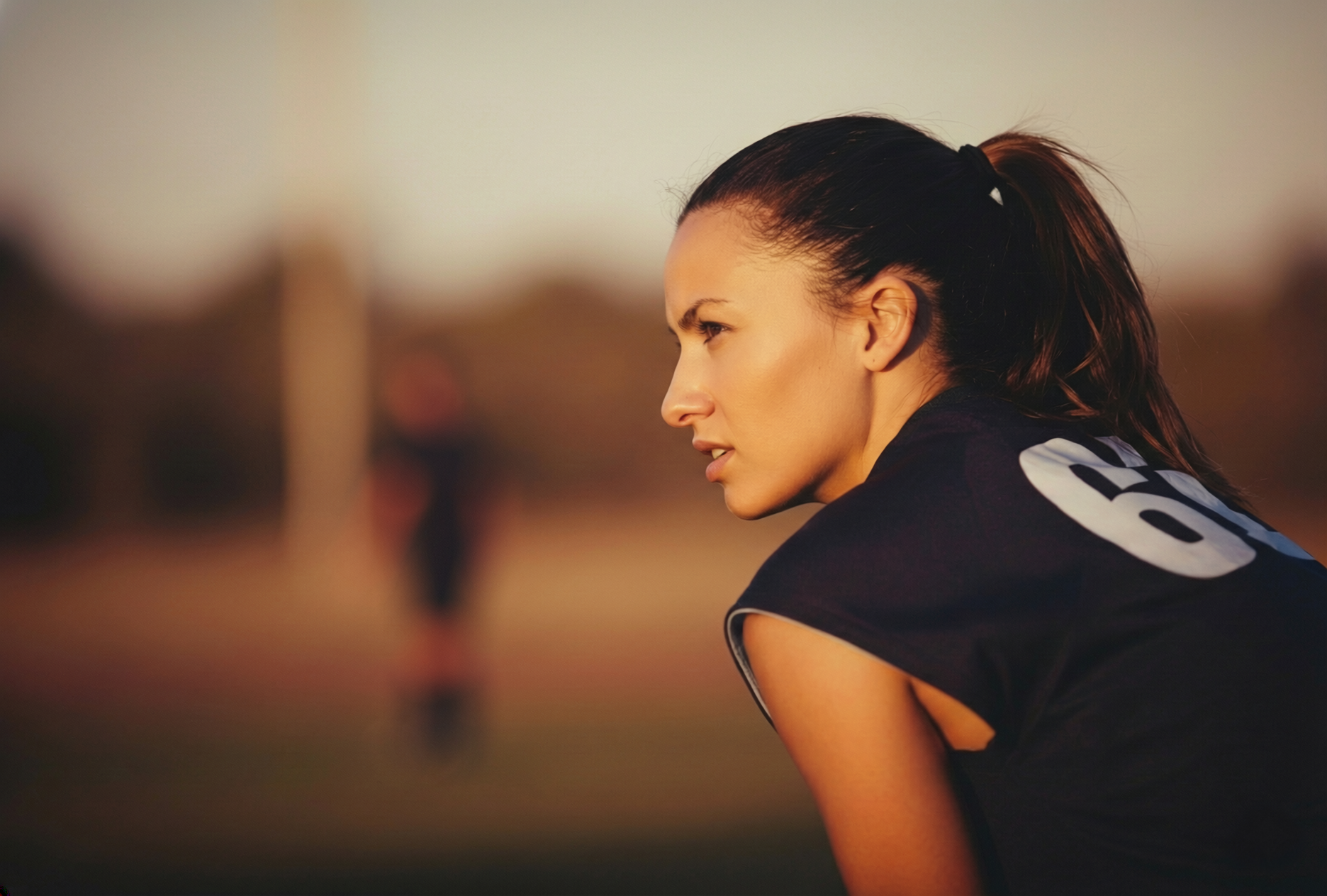Frau auf dem Spielfeld zum Training die sich leicht beugt.